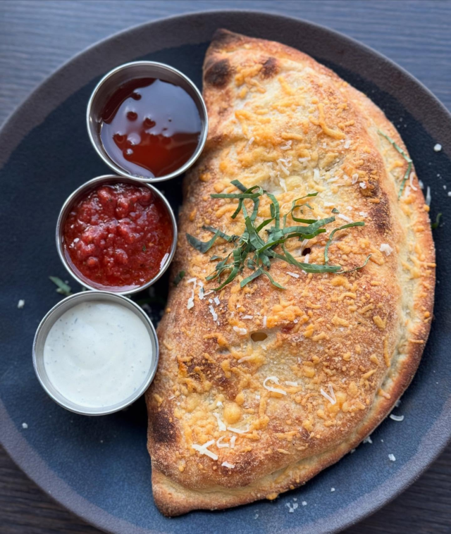 Hot calzones are a Saturday must-have. Grab one for carry out or enjoy dining in with us or taste2ndlanguage 🍕Meat & veggies options available, along with your choice of one of our three house made dipping sauces - Calabrian chili honey, marinara or ranch!